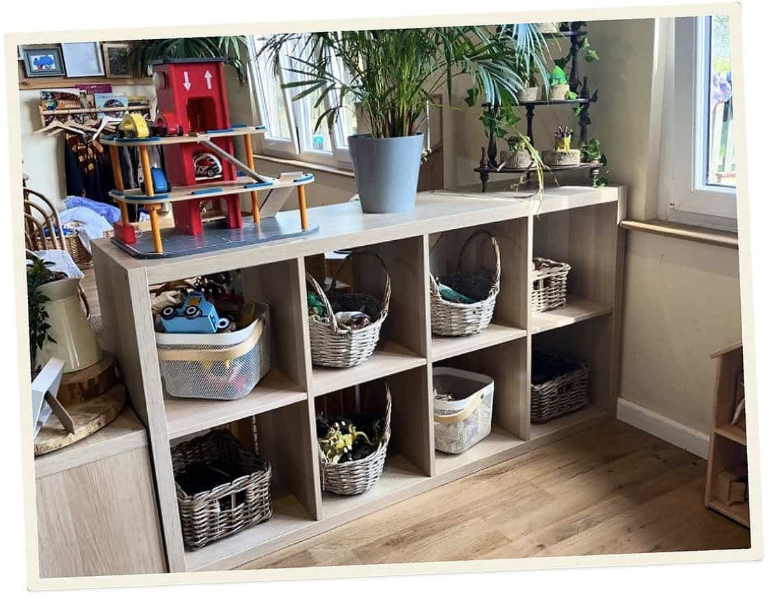 Organised childcare storage with toys, plants, and baskets in a bright room.
