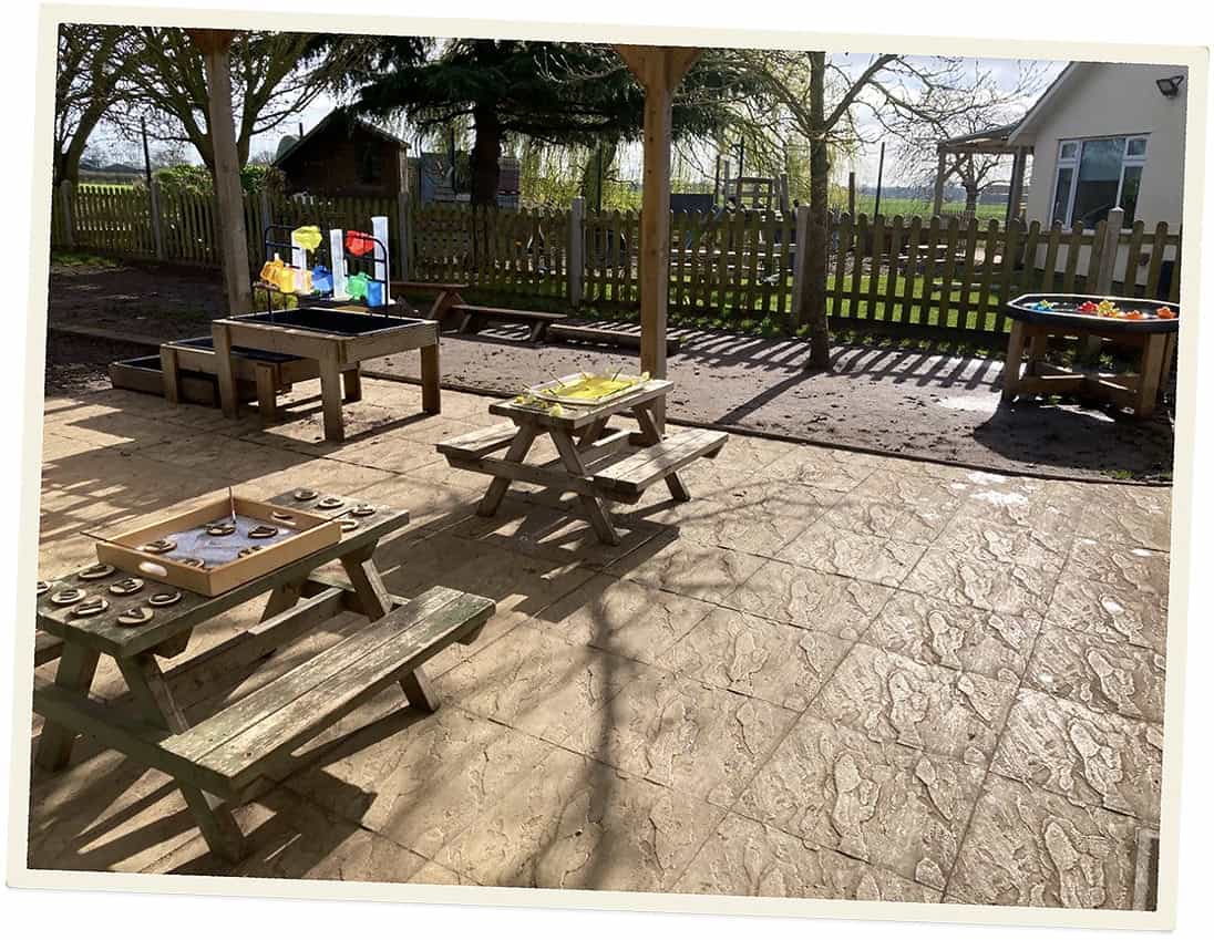 Outdoor play area at Lancaster Lodge Childcare with tables and toys.