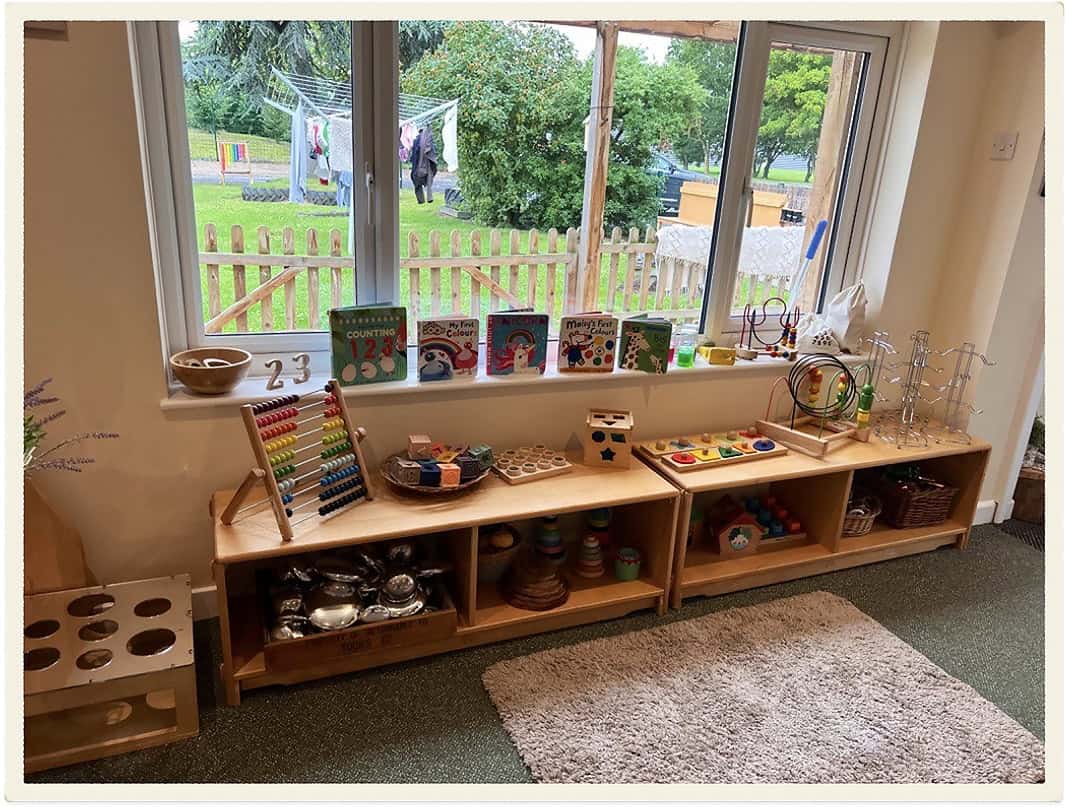 Childcare learning area with educational toys and books by window.