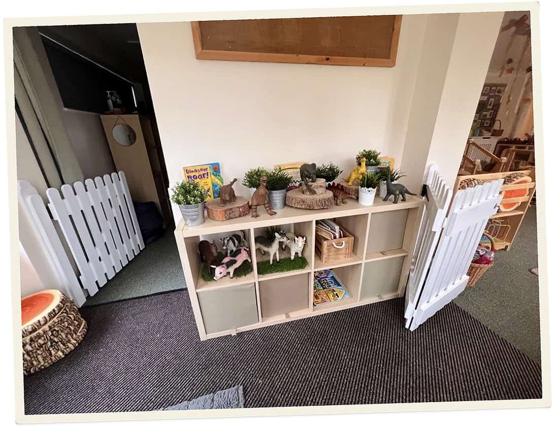 Childcare play area with toys, books, and animal figures in a nursery setting.